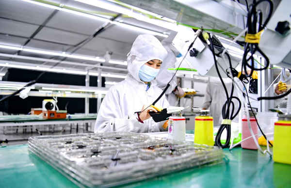Workers produce screens of 5G mobile phones to be exported at a factory in Ganzhou, east China's Jiangxi province, May 13, 2022. (Photo by Zhu Haipeng/People's Daily Online)