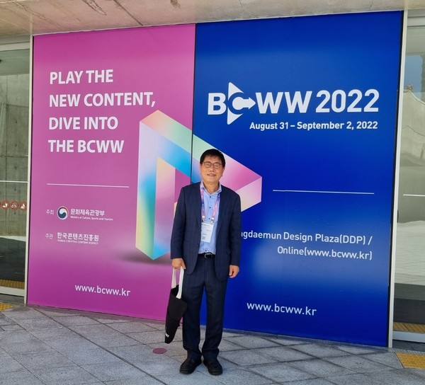 코리아포스트 송나라 부회장이 국제방송영상마켓(BCWW) 2022 포스터 앞에서 기념 촬영하고 있다.