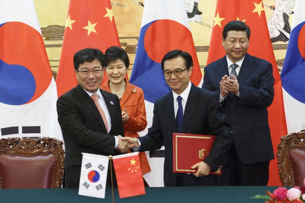 President Park Geun-hye and President Xi Jinping of China (second from left and right, backdrop, respectively) applaude the signing of the the Korea-China Free Trade Agreement after trade ministers from Korea and China sign the document.