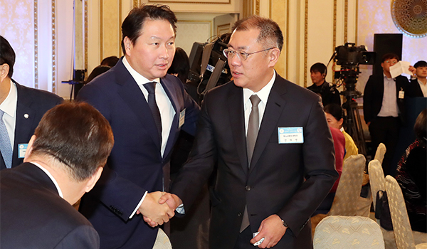 Chairman Chey Tae-won of the SK Group (left, facing the camera) and Chairman Chung Eui-sun of Hyundai Motors shake hands with each other at a meeting. They are among the top leaders in the Korean business world together with Vice Chairman Lee Jae-yong of the Samsung Business Group.