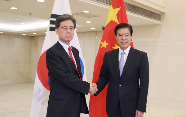 Trade Minister Kim Hyun-chong (left) shakes hands with Chinese Commerce Minister Zhong Shan to discuss stronger Korea-China economic cooperation and trade, in Beijing on June 27, 2022,
