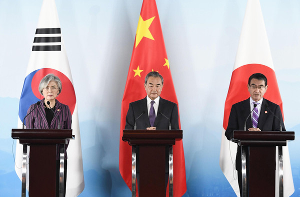 Foreign ministers of the three countries stand side by side in front of their national flags during a foreign ministers' meeting between Korea, China and Japan held in Beijing, China on Aug. 21, 2019. From left, Korean Foreign Minister Kang Kyung-wha, Chinese Foreign Minister Wang Yi, and Japanese Foreign Minister Taro Kono.
