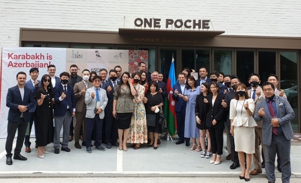 Madam Konul Teymurova (spouse of the ambassador of Azerbaijan in Seoul) is seen fifth from left at the front row with the ambassadors and their spouses together with Korean guests at a meeting where the sign in the backdrop reads, “Karabakh is Azerbaijan.” Ambassador Ramzi Teymurov is seen stabdubg second from the flag of Azarbaijan in the rear.
