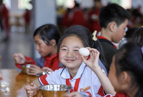 Students are having meals at a primary school at a relocation site for poverty alleviation in Kaiyang county, Guiyang, southwest China's Guizhou province, May 2022. The county offers free meals for students. Each meal includes three dishes and a bowl of soup, as well as a fruit or a cup of milk. (Photo by Yuan Fuhong/People's Daily Online)