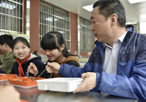 The party head of a primary school in Shushan district, Hefei, east China's Anhui province has a meal together with students, March 2019.The primary school invites students' parents to "test" meals supplied at school to ensure food safety. (Photo by Ge Yinian/People's Daily Online)