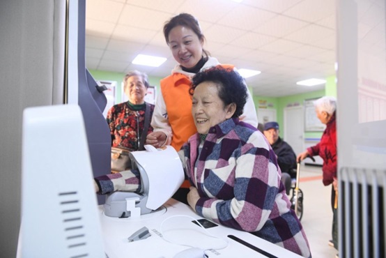 A senior woman has her blood pressure measured at a day-care nursing home under the instruction of a staff member in Lianchi community, Wenfeng neighborhood, Yingzhou district, Fuyang, east China's Anhui province, October 2021. (Photo by Wang Biao/People's Daily Online) 