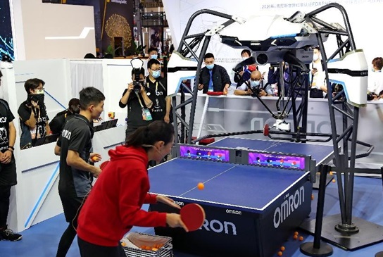 A woman plays ping pong with a ping pong robot developed by Omron at the fourth China International Import Expo, Nov. 6, 2021. (Photo by Xu Congjun/People's Daily Online)