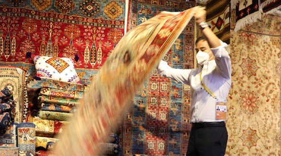A man showcases a handmade carpet from Afghanistan. (By Gu Haimin/People's Daily Online)