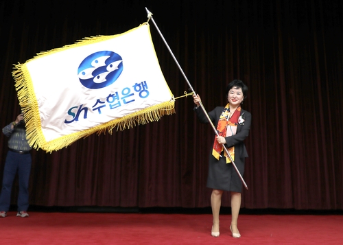 President Kang Shin-sook of Suhyup Bank waves the flag of the bank after being officially appointed as the head of the bank at the general meeting of the National Federation of Fisheries Cooperatives on Nov. 17.