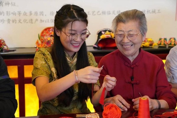 Sun Geyao, a fifth-generation inheritor of the national intangible cultural heritage Xuzhou sachet from Xuzhou, east China's Jiangsu province, makes a sachet with her grandmother Wang Xiuying, who's also an inheritor of the traditional craft. (Photo from Yangtse Evening Post)