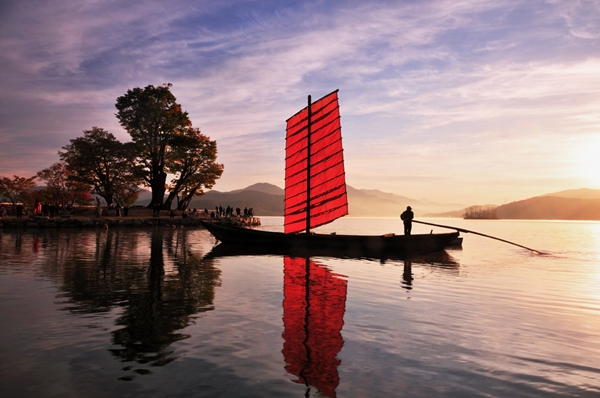 A traditional Korean sail boat passing the Dumumeori area against the beautiful scene of the sunset.Yangpyeong Dumulmeori