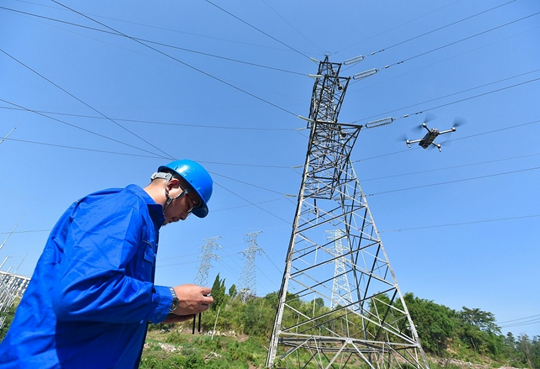 A staff member of the Neijiang Power Supply Company of the State Grid operates a drone to inspect transmission lines in Neijiang, southwest China's Sichuan province, August 2022. (Photo by Huang Zhenghua/People's Daily Online)