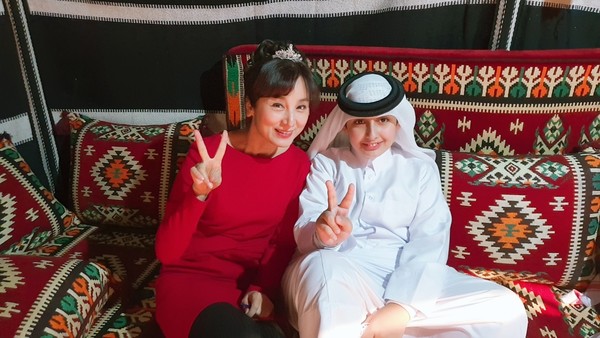 Editorial Writer Jenny Jang (left) makes a victory sign with a child of the Qatar.