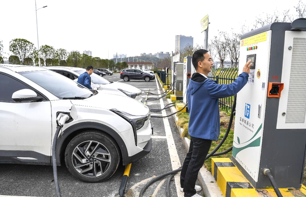 A man charges an electric vehicle in a parking lot in Fengxin county, Yichun, east China's Jiangxi province, Nov. 21, 2022. (Photo by Zhou Liang/People's Daily Online)