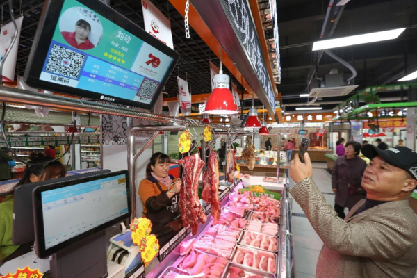 A man scans a QR code to buy meat in a farmers' market in Xiangzhou district, Xiangyang, central China's Hubei province. (Photo by Yang Dong/People's Daily)
