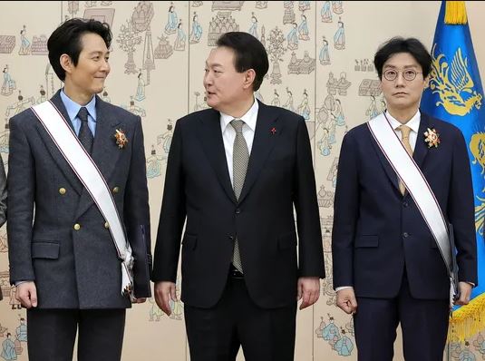 President Yoon Suk-yeol (center) take a commemorative photo with director Hwang Dong-hyuk (right) and actor Lee Jung-jae, who won an Emmy Award for the drama "Squid Game," after awarding the top cultural medal at the presidential office in Yongsan on Dec. 27.