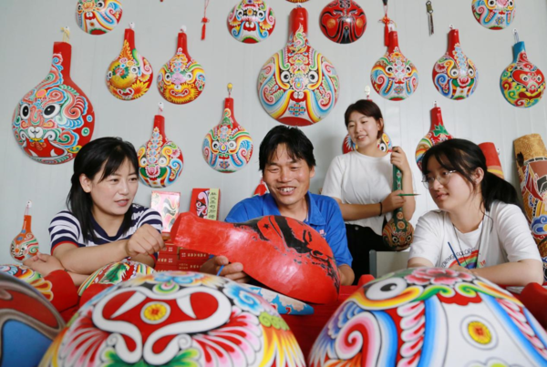Ma Long (second from left), an inheritor of ladle mask making, a provincial-level intangible cultural heritage item, instructs college students to make masks in a ladle mask workshop in Mashan village, Yinxing township, Huixian county, Longnan, northwest China's Gansu province, July 13, 2022. (Photo by Li Xuchun/People's Daily Online)