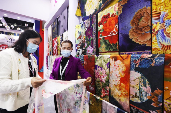 A purchaser buys silk scarves at the 28th China Yiwu International Commodities Fair, Nov. 24, 2022. (Photo by Gong Xianming/People's Daily Online)
