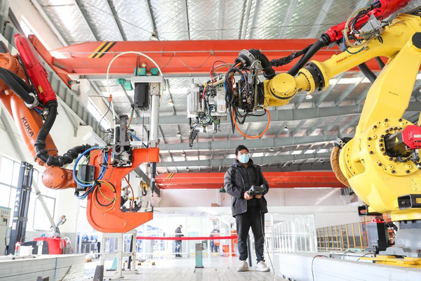A worker controls robotic arms to manufacture products in a workshop of an intelligent technology company in Shanghai, Jan. 10, 2023. (Photo by Jiang Huihui/People's Daily Online)