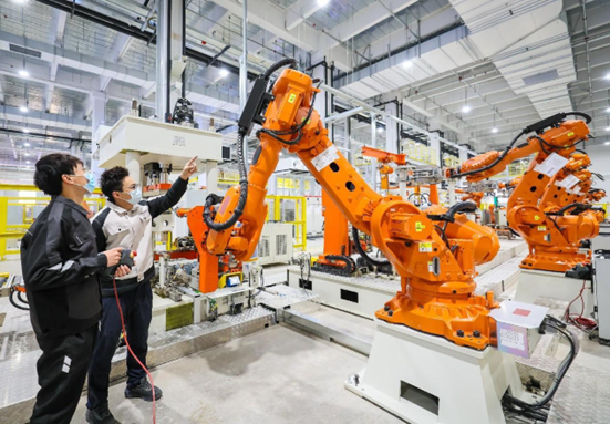 A smart washing machine factory of Chinese home appliance giant Haier is put into use in Songjiang district, Shanghai, Dec. 29, 2022. Photo shows technicians debugging robotic arms. (Photo by Cai Bin/People's Daily Online)