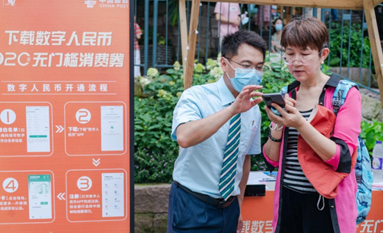 An employee of the Postal Savings Bank of China instructs a citizen to get red packets on the application of China's digital fiat currency in southwest China's Chongqing municipality. (Photo by Li Hongbo/People's Daily Online)