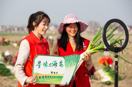 A volunteer and Party head (right) of Hangyao village, Hai'an, east China's Jiangsu province, sell long green onions on a livestream platform, March 7, 2023. (Photo by Zhai Huiyong/People's Daily Online)