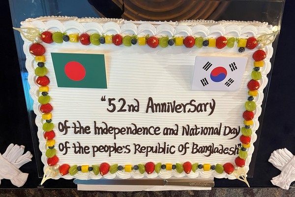 National flags of Korea and Bangladesh are displayed on the top of a large celebration cake at the reception venue attracting the attention of many guests.