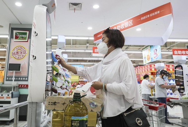 A woman pays on a self-checkout in a supermarket in Huai'an, east China's Jiangsu province. (Photo by Zhao Qirui/People's Daily Online)