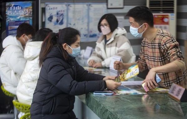 Citizens learn about outbound travel packages in a travel agency in Taizhou, east China's Jiangsu province, Feb. 9, 2023. (Photo by Tang Dehong/People's Daily Online)