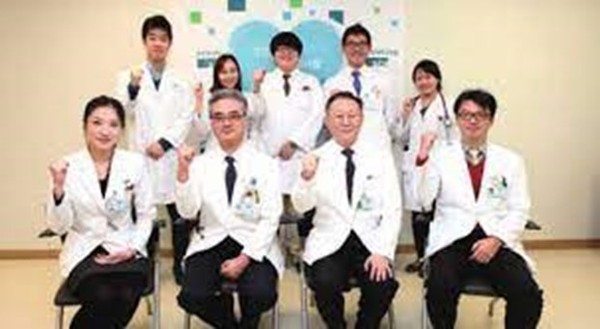 Prof. Dr. Roh Hakjae (seated second from left, front row) makes a win-win gesture with other doctors of the Soonchunhyang General Hospital in Seoul with other doctors of the Hospital. He listens to the patients and wins their admiration for his careful attention given to each of them.