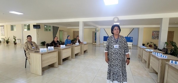  Observers sit on the left side of the entrance to the polling place. Mirmuhammedova Shahlo, who is in charge of this polling station, stands at the center.
