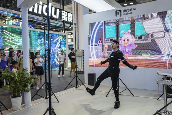 A staff member of an exhibitor drives a virtual figure with a motion-capturing device at the 2023 World Artificial Intelligence Conference in Shanghai, July 6. (Photo by Wang Chu/People's Daily Online)