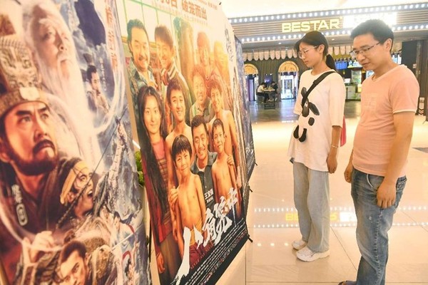 Moviegoers watch posters in front of a cinema in Fuyang, east China's Anhui province, July 2, 2023. (Photo by Wang Biao/People's Daily Online)