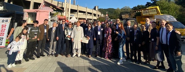 Visiting members of the Seoul Diplomatic Corps pose for the camera in front of the indoor stadium of the Cheonan City.