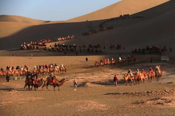 Tourists visit the Yueya Spring scenic area, a crescent-shaped lake surrounded by giant sand dunes, in Dunhuang, northwest China's Gansu province, Oct. 13, 2023. (Photo by Zhang Xiaoliang/People's Daily Online)