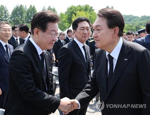 President Yoon Suk Yeol (R) shakes hands with opposition leader Lee Jae-myung at a Memorial Day event at Seoul National Cemetery in Seoul in this file photo taken June 6, 2023. (Yonhap)