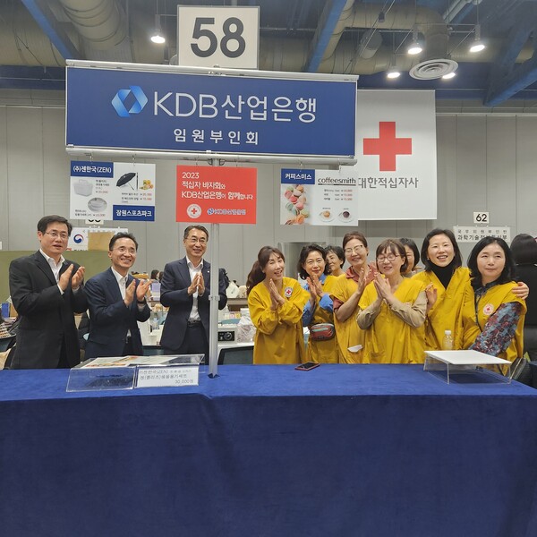 Industrial Bank of Korea employees and Red Cross volunteer wives raise a cheer of joy after selling all the goods on display.