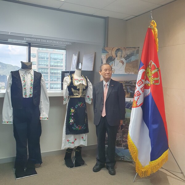 Publisher-Chairman Lee Kyung-sik of The Korea Post media poses with the National Flag of the Republic of Serbia (right) and the traditional costumes of man and woman of Serbia (left and right).