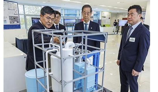 Prime Minister Han Duck-soo (C) listens to an official explaining technology to produce clean methanol before attending the presidential committee on carbon neutrality meeting in Seoul on Nov. 23, 2023.