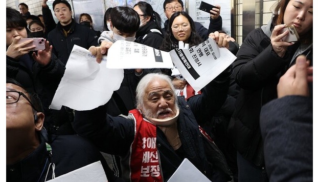 Park Kyoung-seok (C), the 63-year-old leader of Solidarity Against Disability Discrimination, rips apart a petition to submit to the state human rights watchdog after the group was asked to leave by the police and Seoul Metro employees on Nov. 28, 2023.