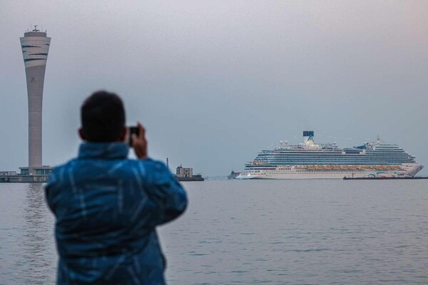 The Adora Magic City, China's first domestically-made large cruise ship, departs from Shanghai Wusongkou International Cruise Terminal for its first commercial voyage on Jan 1, 2024. Photo shows a man taking pictures of the ship. (Photo by Wang Chu/People's Daily Online)