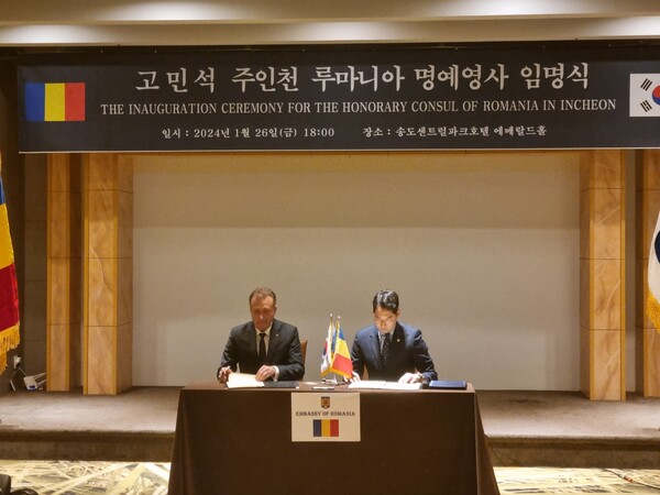 Ko Min-seok  signs documents  as a Honoray Cousul  with the Romanian Ambassador to Korea at the appointment ceremony of the Honorary Consul General of Romania.