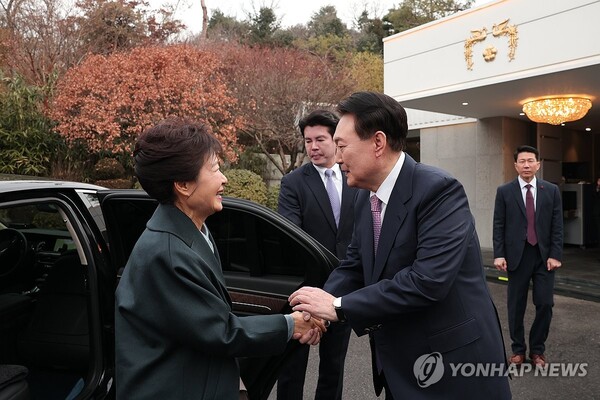 President Yoon Suk Yeol (R) welcomes former President Park Geun-hye at his official residence in Seoul on Dec. 29, 2023, as she arrives for a luncheon with Yoon, in this photo released by the presidential office. (PHOTO NOT FOR SALE) (Yonhap)