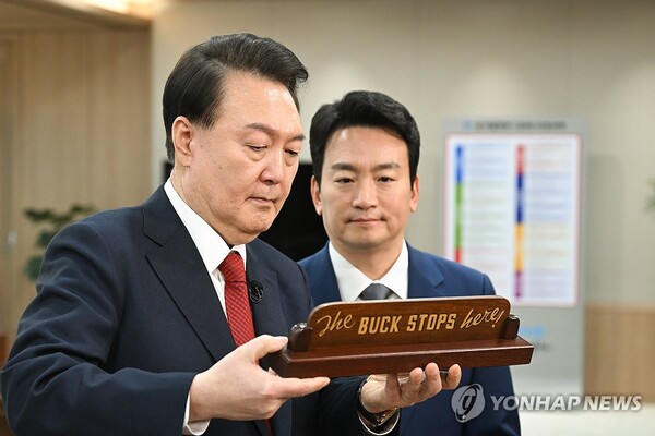President Yoon Suk Yeol (L) introduces a replica of Truman's "The Buck Stops Here" desk plaque, gifted by U.S. President Joe Biden during summit talks in Seoul in May 2023, to a KBS anchorman after recording a special interview with the state-run broadcaster at the presidential office in Seoul on Feb. 4, 2024, in this photo provided by the office.  (Yonhap)
