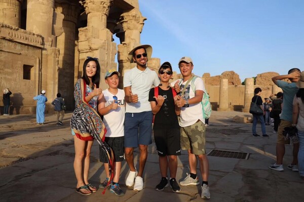 Chinese tourists pose for a picture with an Egyptian tour guide in front of the Luxor Temple in Egypt. (Photo provided by Abbas El-Said)