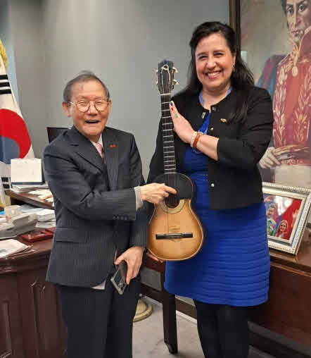 Ambassador Carlo Quero of Venezuela (right) is holding her favorite ukelele, on which Publisher Lee of The Korea Post media tries his hand.