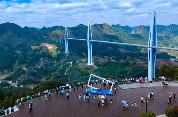 Tourists visit the Pingtang grand bridge in southwest China's Guizhou province. (Photo by Jia Zhi/People's Daily Online)