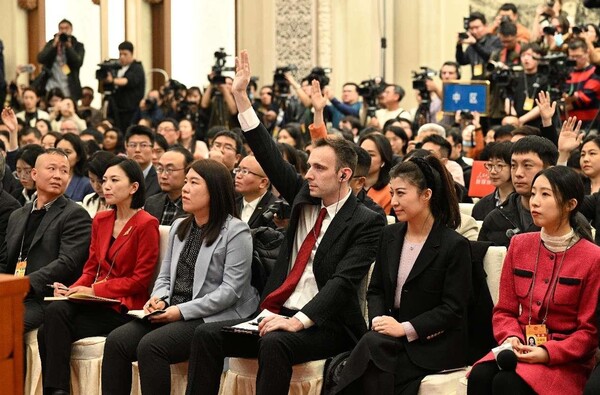 Chinese and foreign journalists raise their hands to ask questions at a press conference of the second session of the 14th National Committee of the Chinese People's Political Consultative Conference, March 3, 2024. (Photo by Lei Sheng/People's Daily)