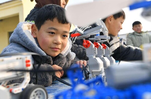 Students watch a robot performance in a elementary school in Handaokou township, Xiayi county, central China's Henan province. (Photo by Miao Yucai/People's Daily Online)
