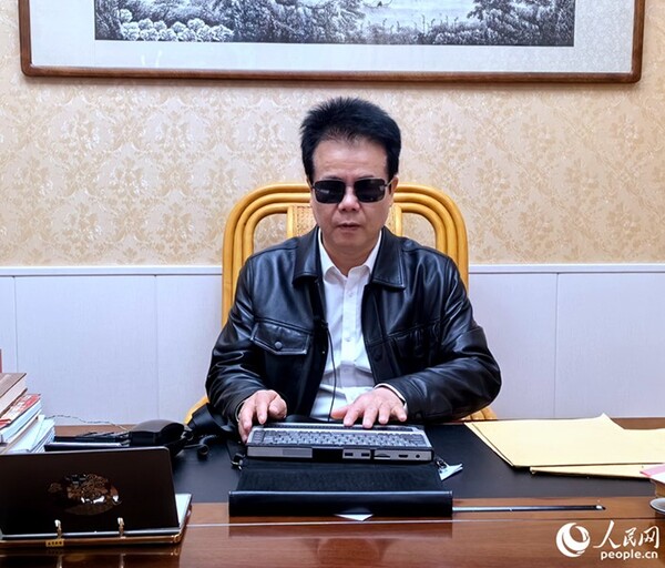 Wang Yongcheng, a deputy to the 14th National People's Congress, uses a computer for persons with visual impairments. (Photo by Lin Xiaoli/People.cn)